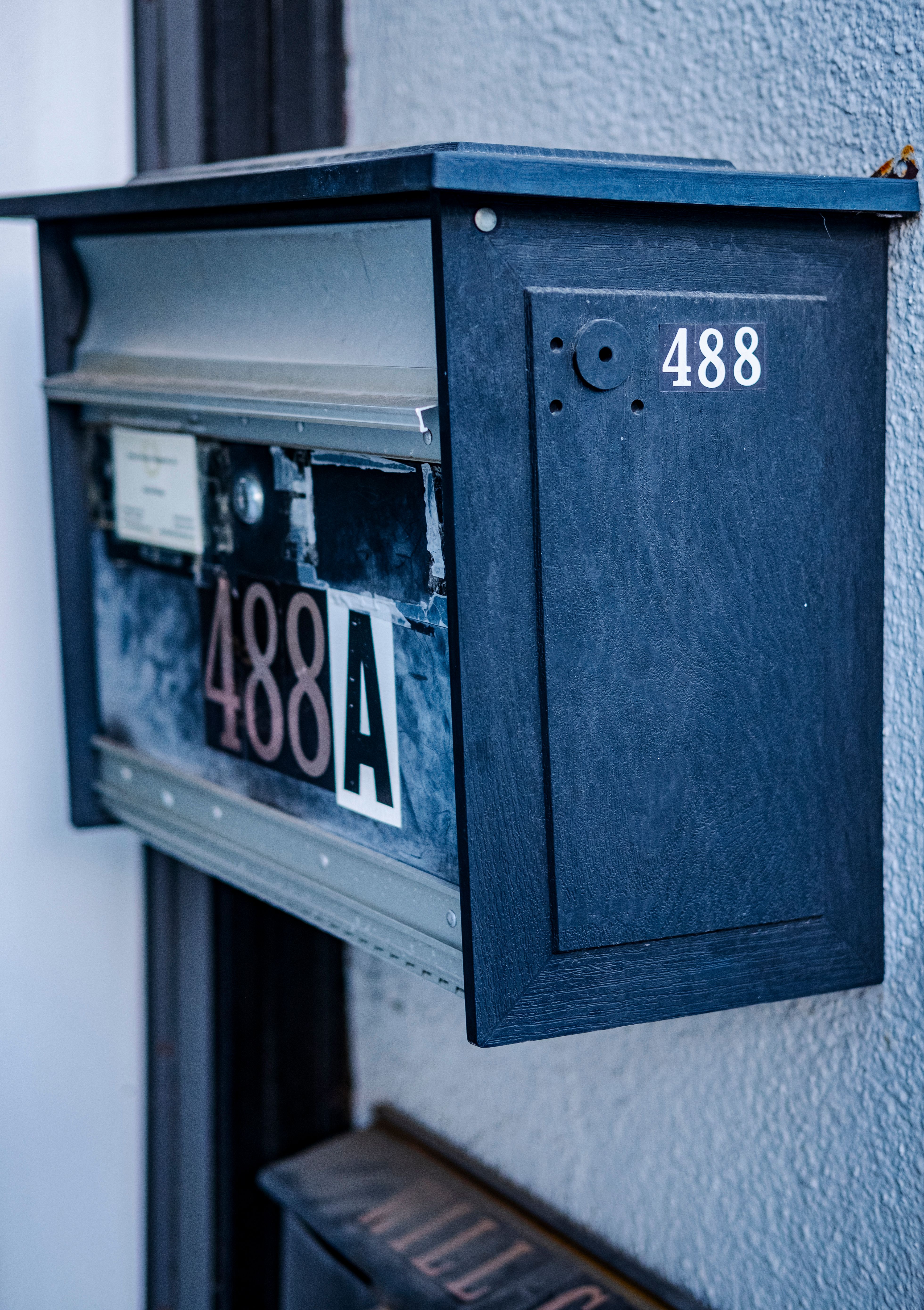 Blue metal mailbox with house number 488 on a textured wall captured in a vertical shot.