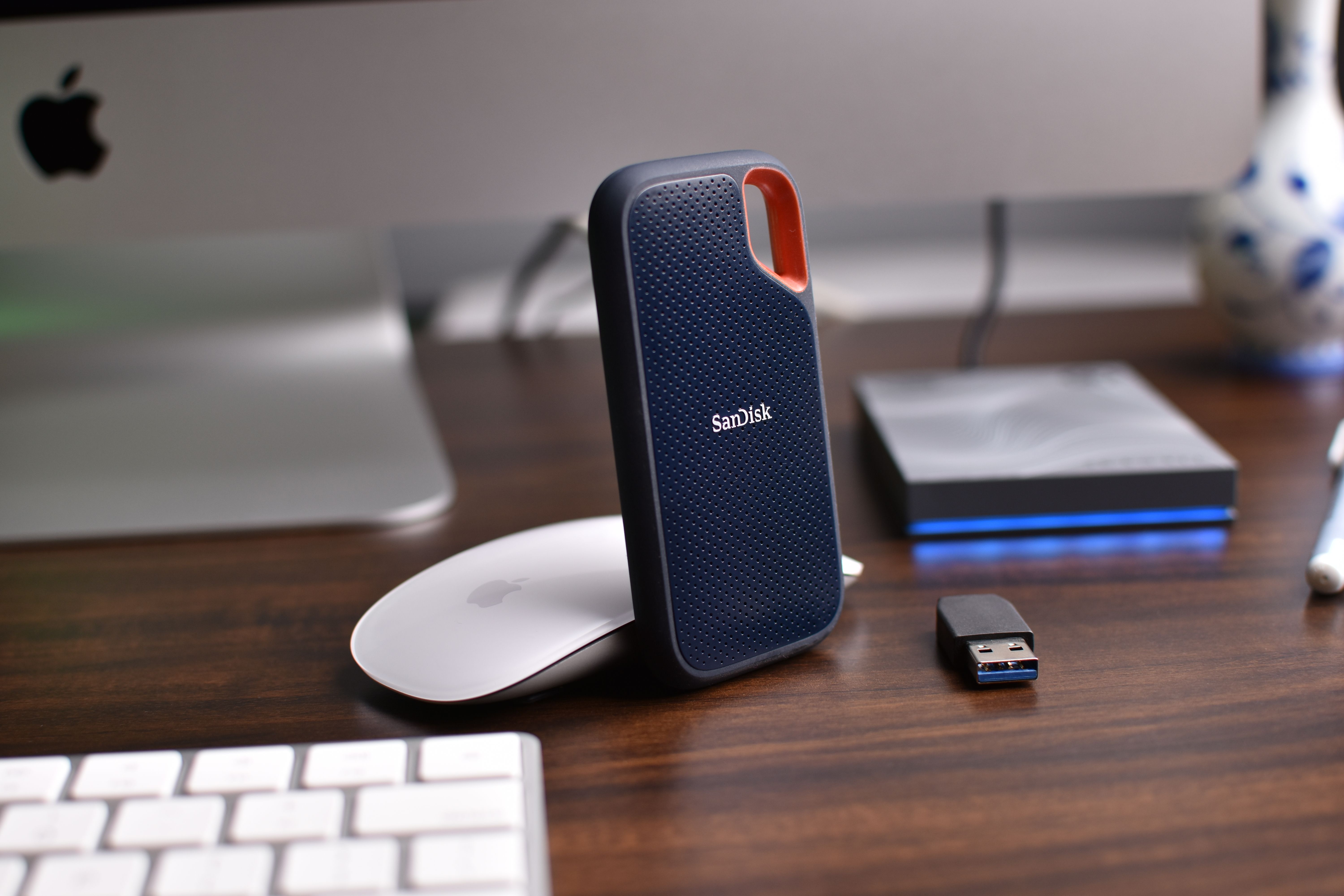 Close-up of a desk setup featuring external hard drives, mouse, and USB stick.