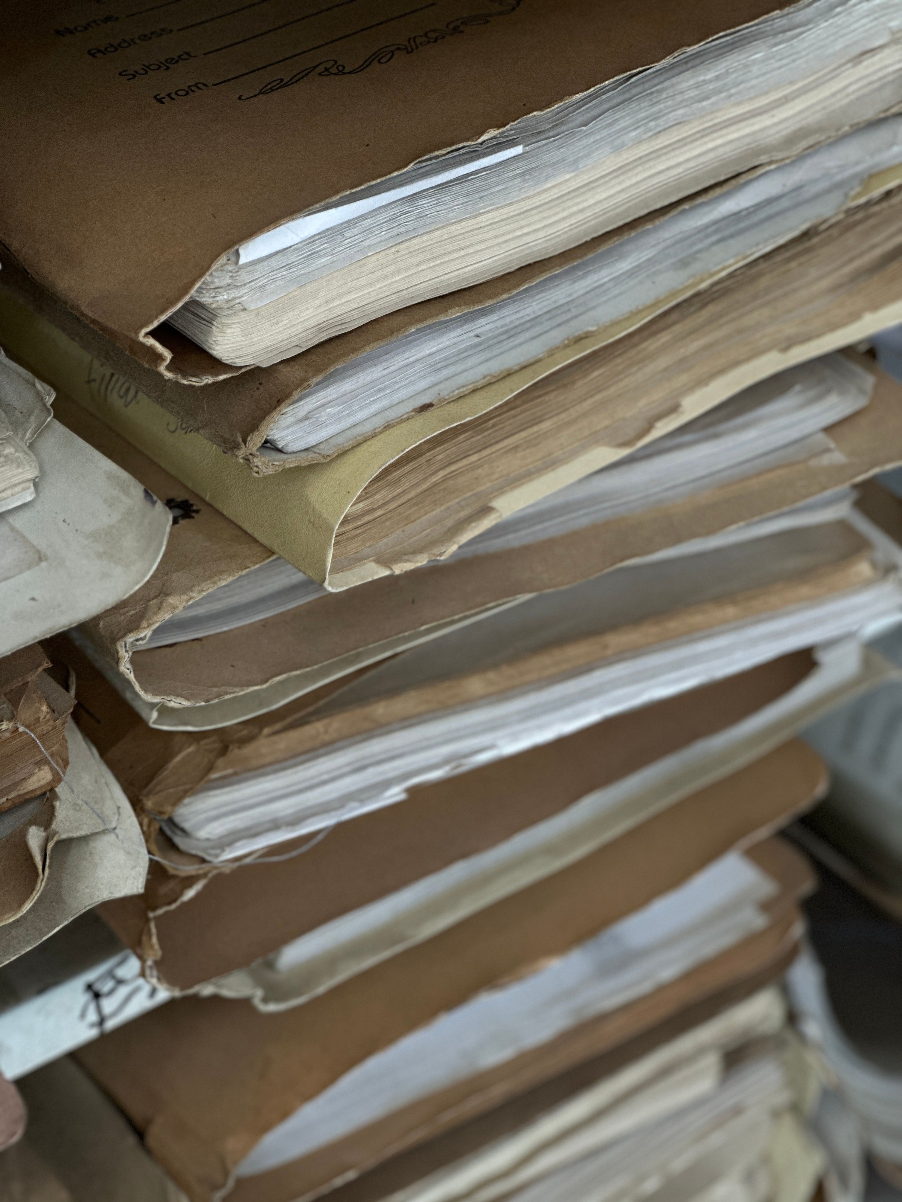 Close-up of old paper files stacked in vintage brown folders, organized and archived.