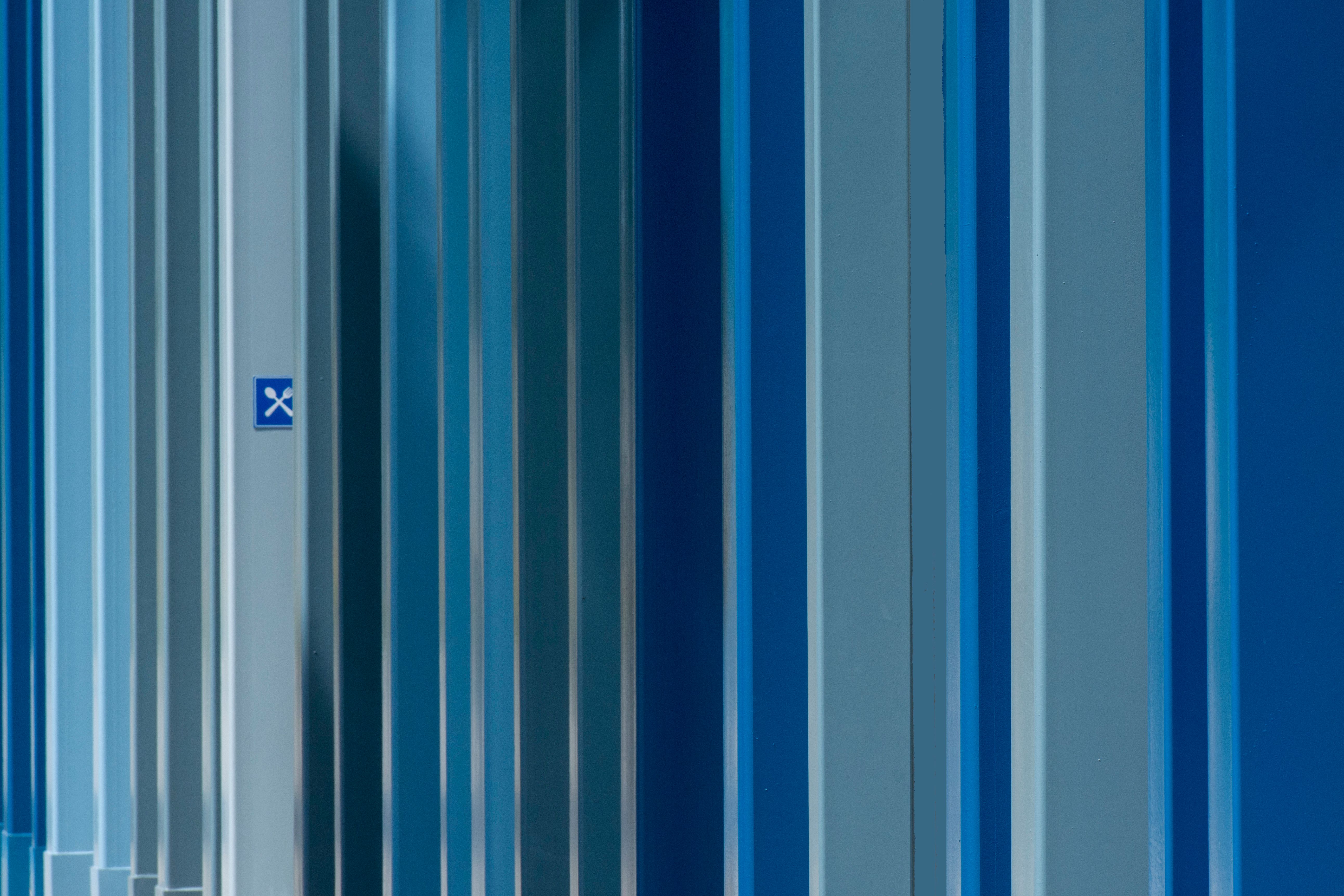 Close-up of blue metal surface with vertical stripes and texture, offering a geometric abstract view.