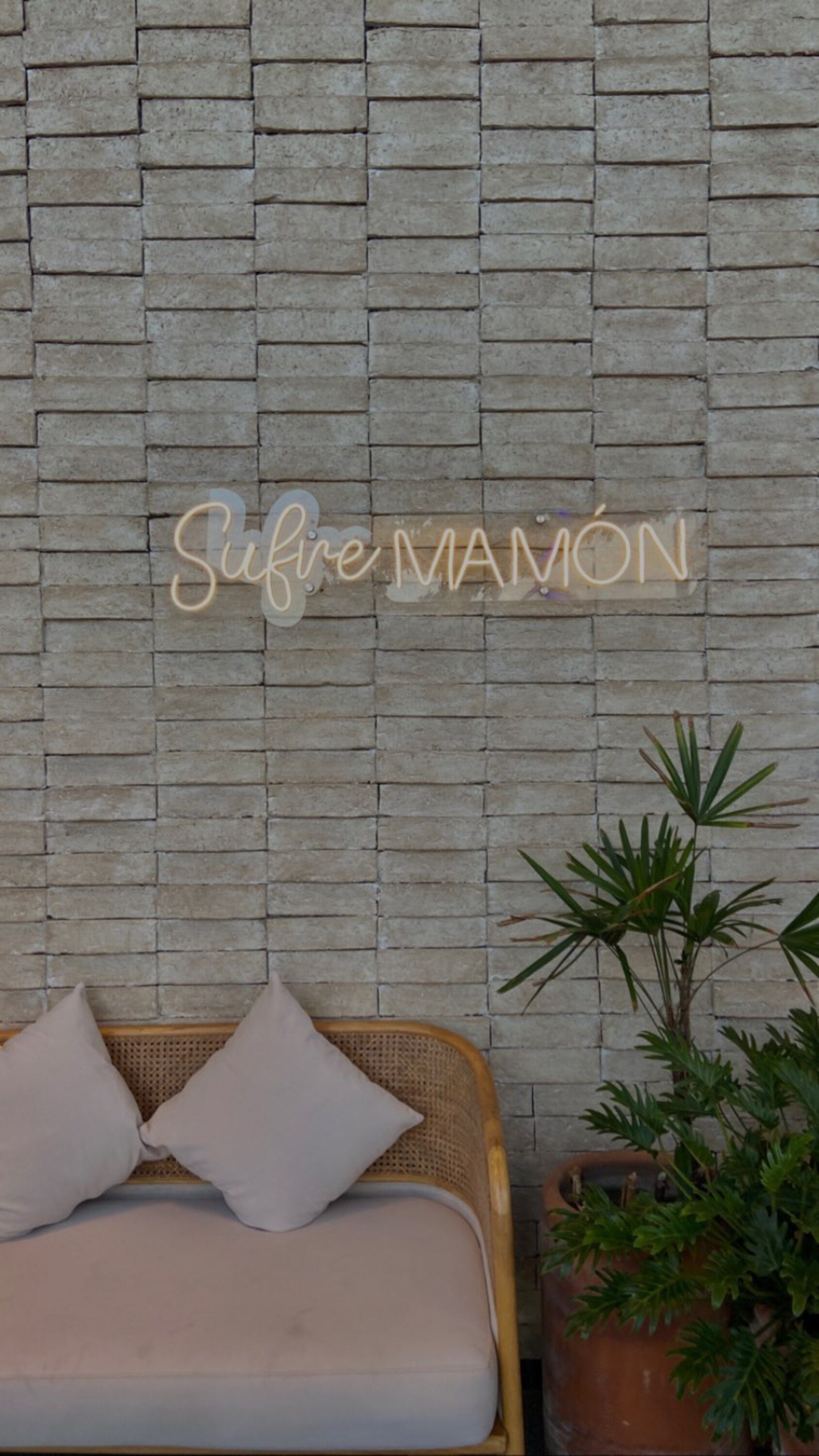 Stylish lounge featuring a neon sign and cozy seating against a textured wall.