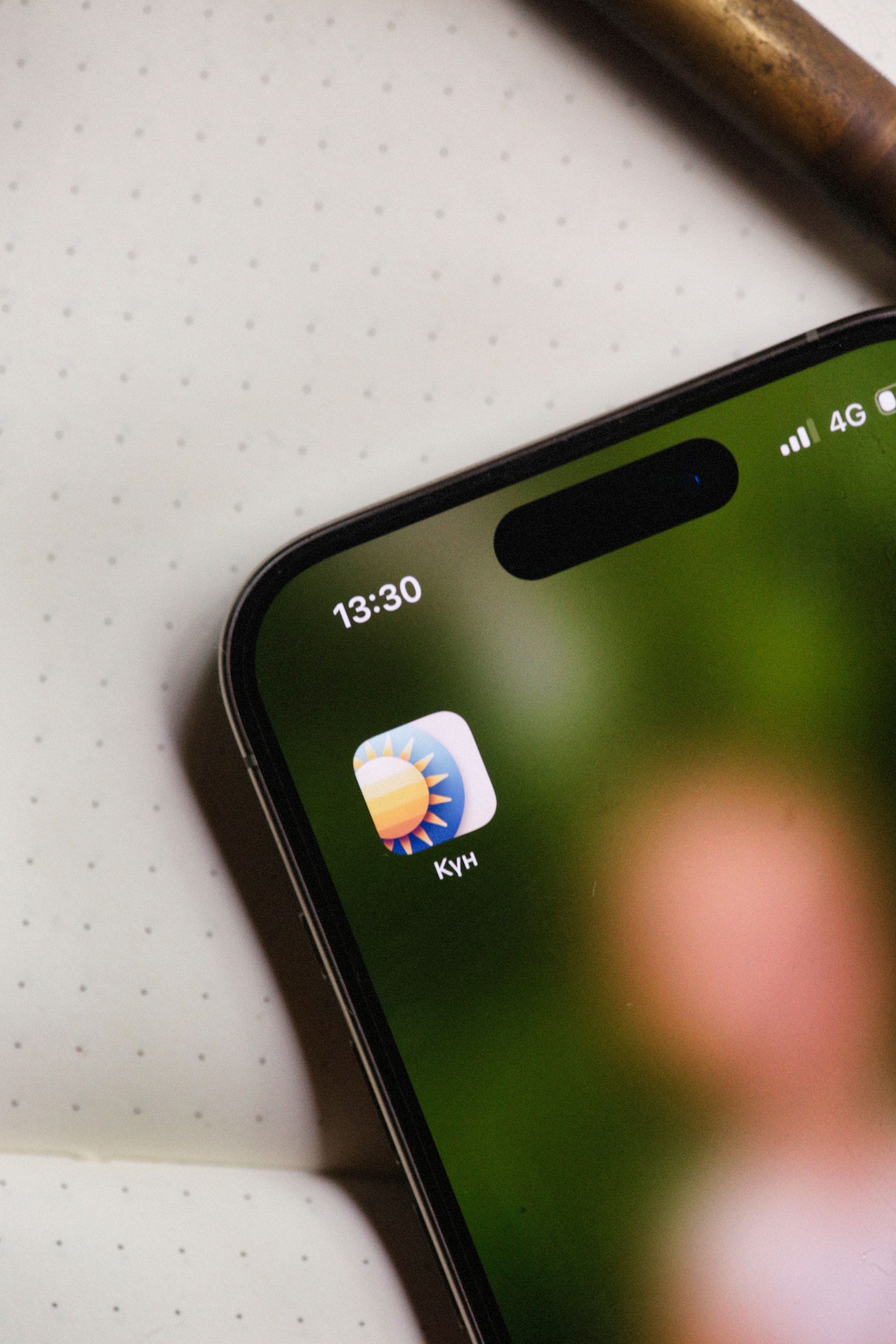 Close-up of a smartphone showing a weather app icon and blurred background.