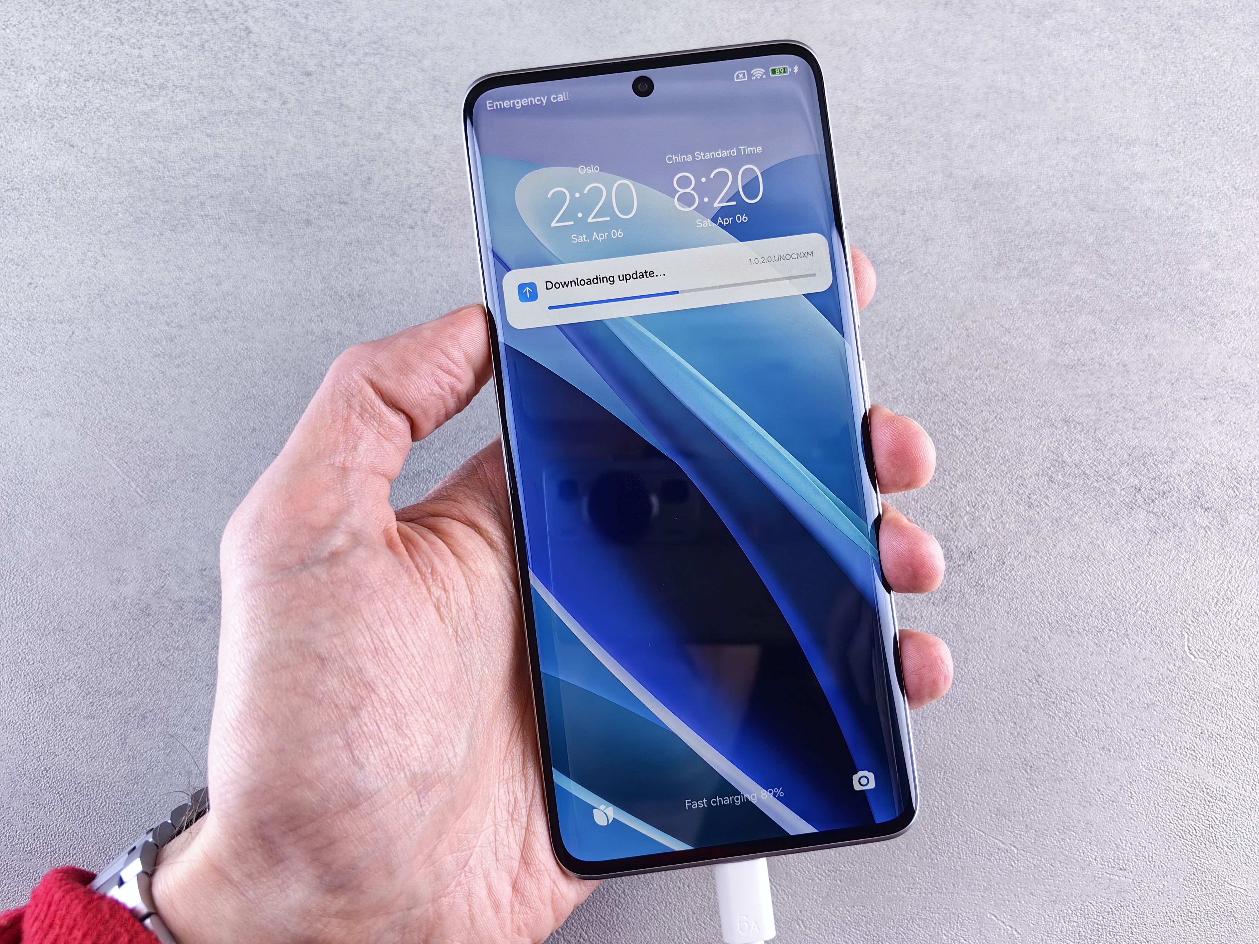 Close-up of a hand holding a smartphone with a downloading update notification on the screen.