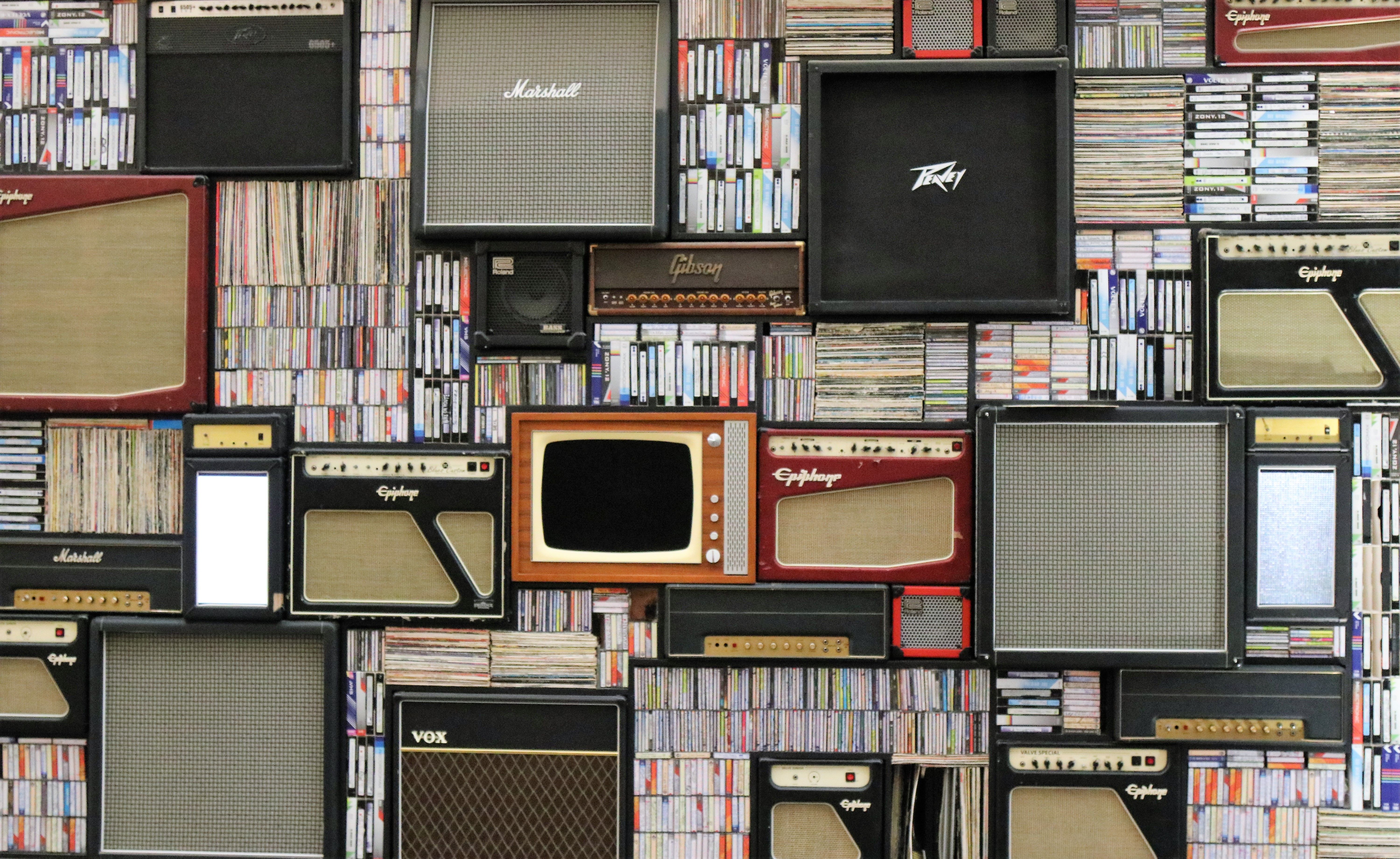 A wall of vintage speakers and TVs surrounded by books and records in a creative display.