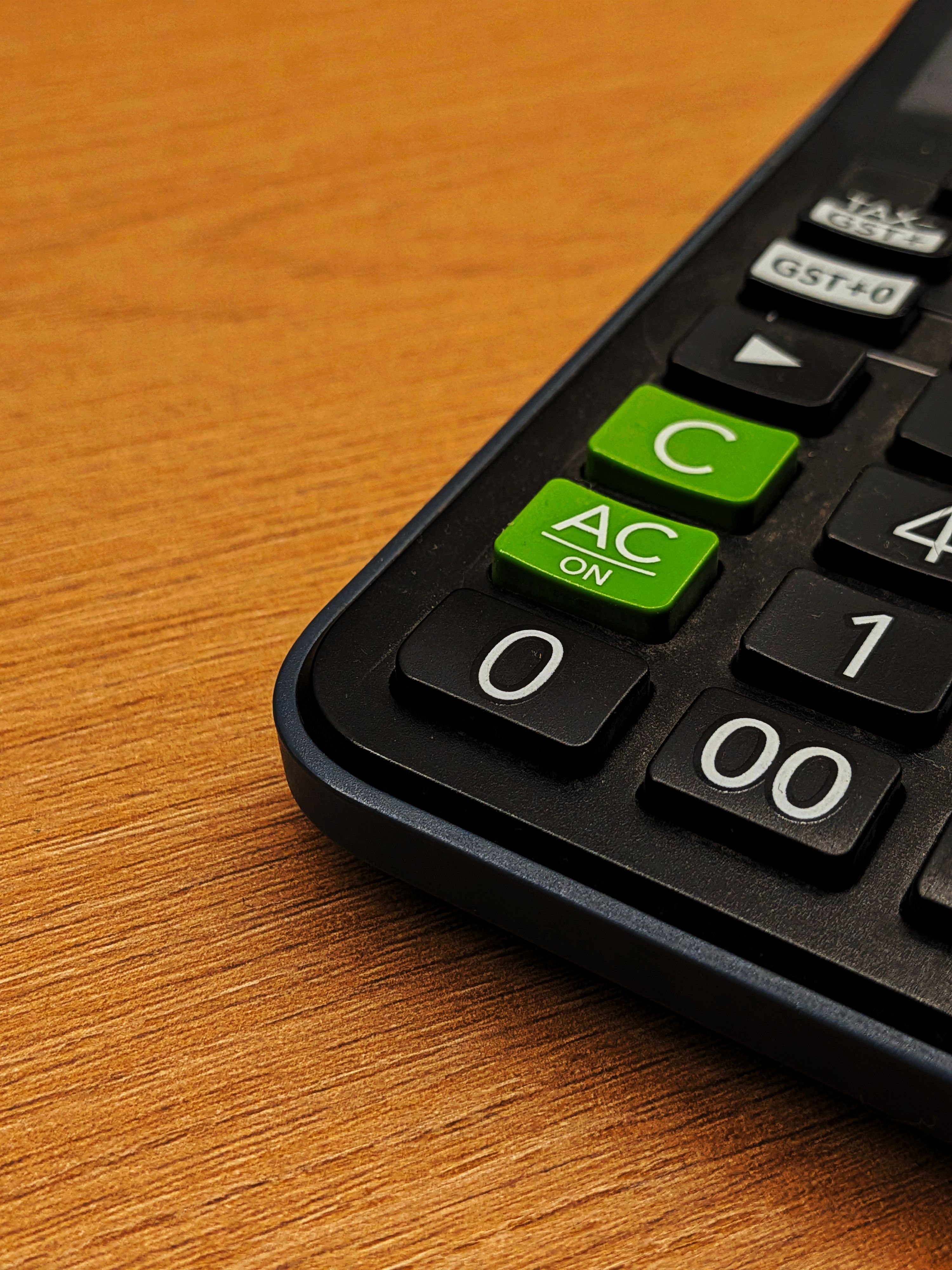 Detailed image of a calculator with green and black keys on a wooden surface.