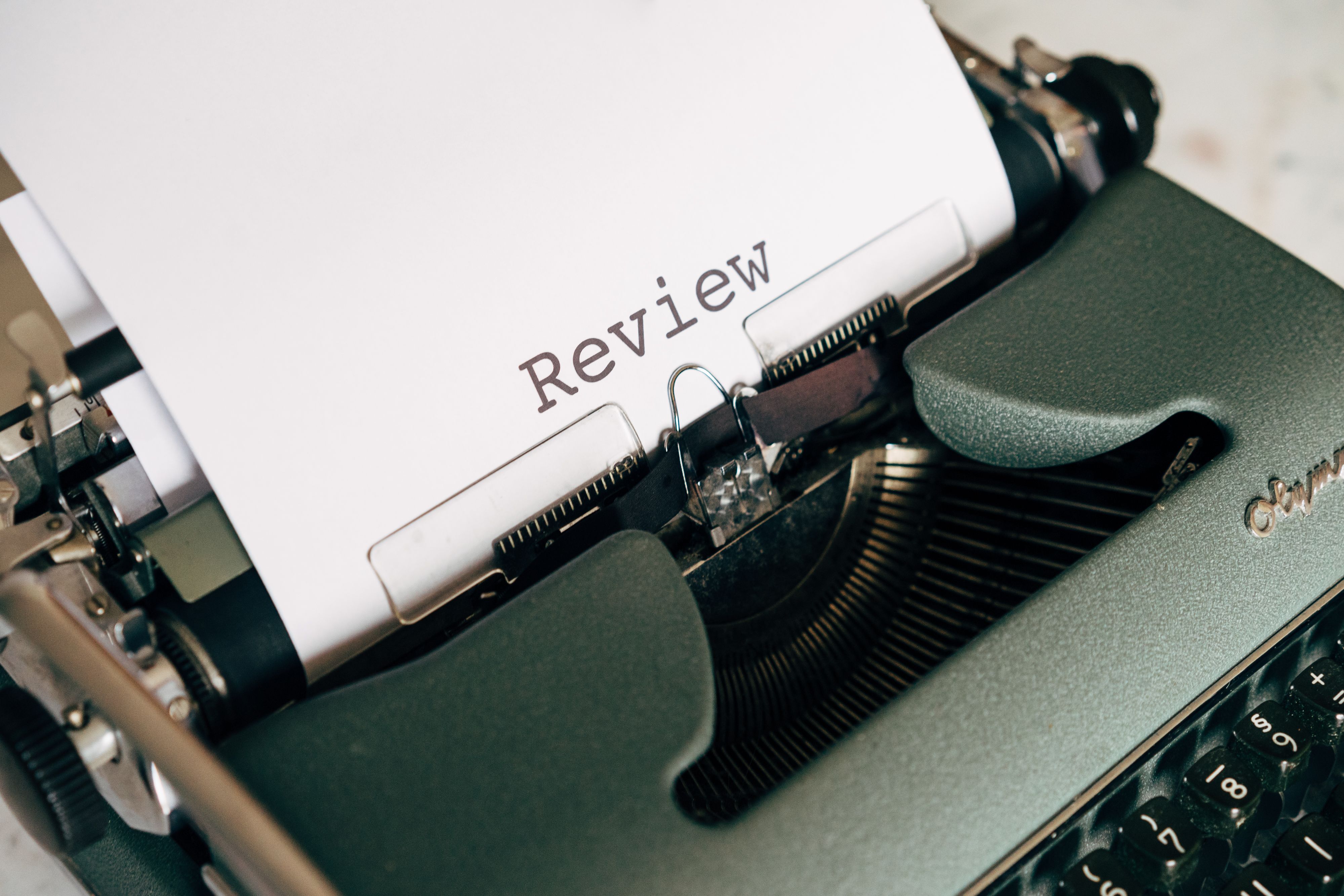 Close-up of an antique typewriter printing the word 'Review' on white paper.
