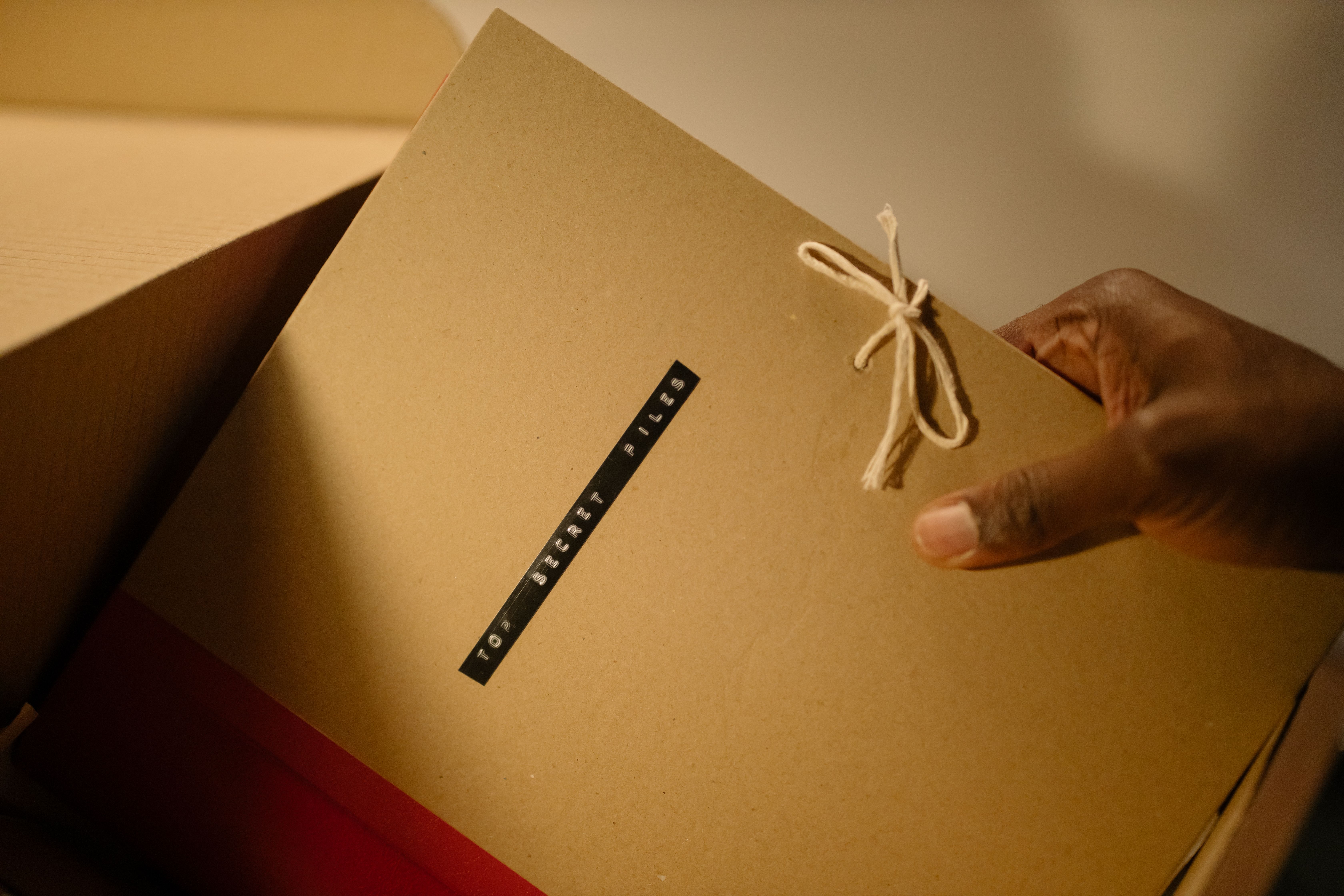 Close-up of hand holding top secret document folder in a box.