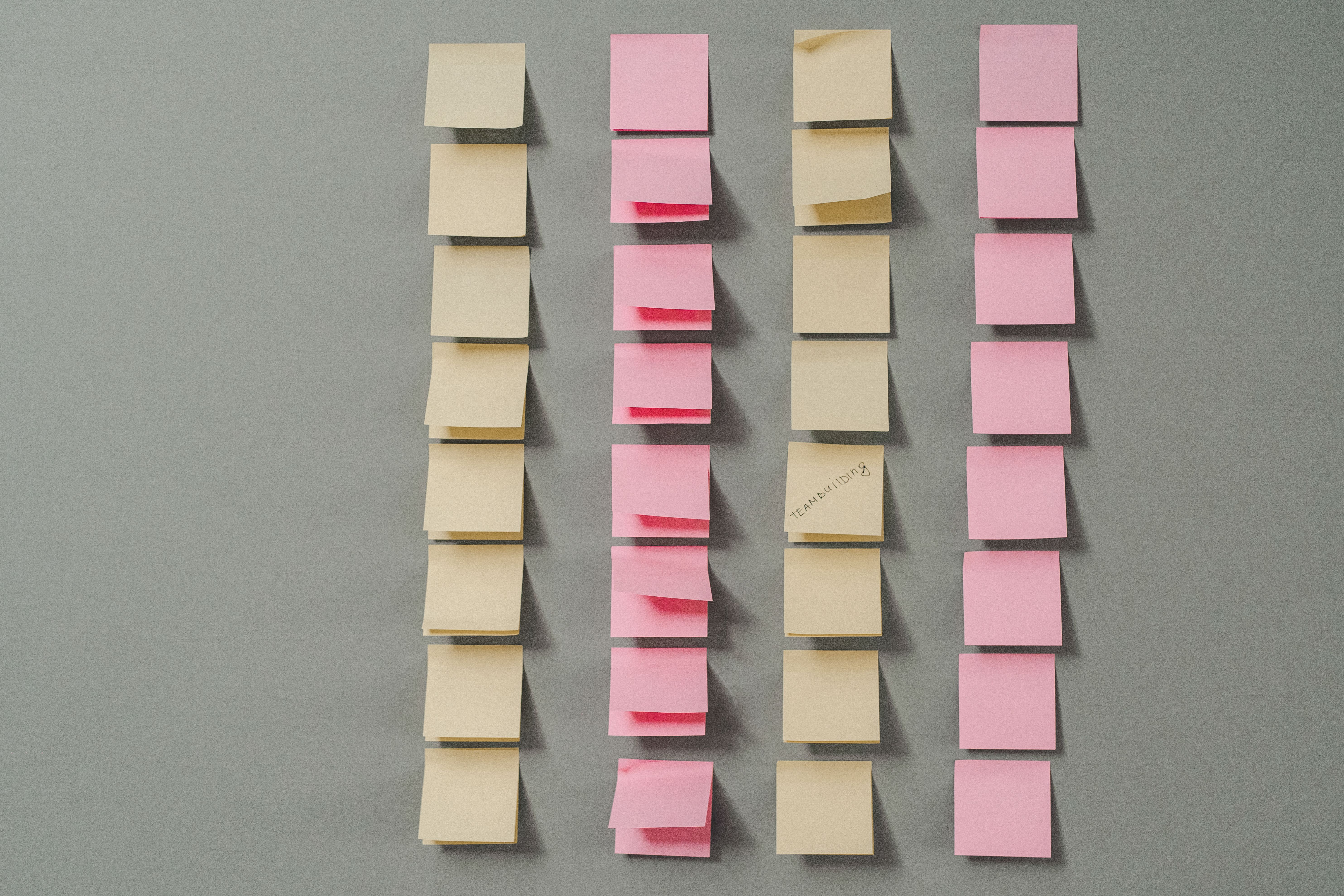 Rows of pink and yellow sticky notes on a gray background, ideal for planning concepts.